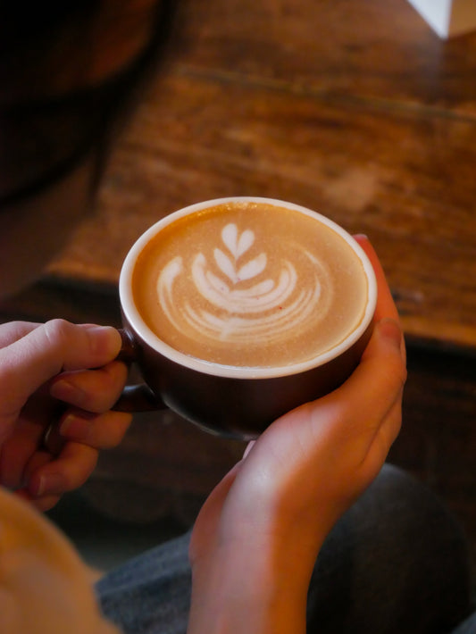 shot from behind a person holding a latte with latte art on top